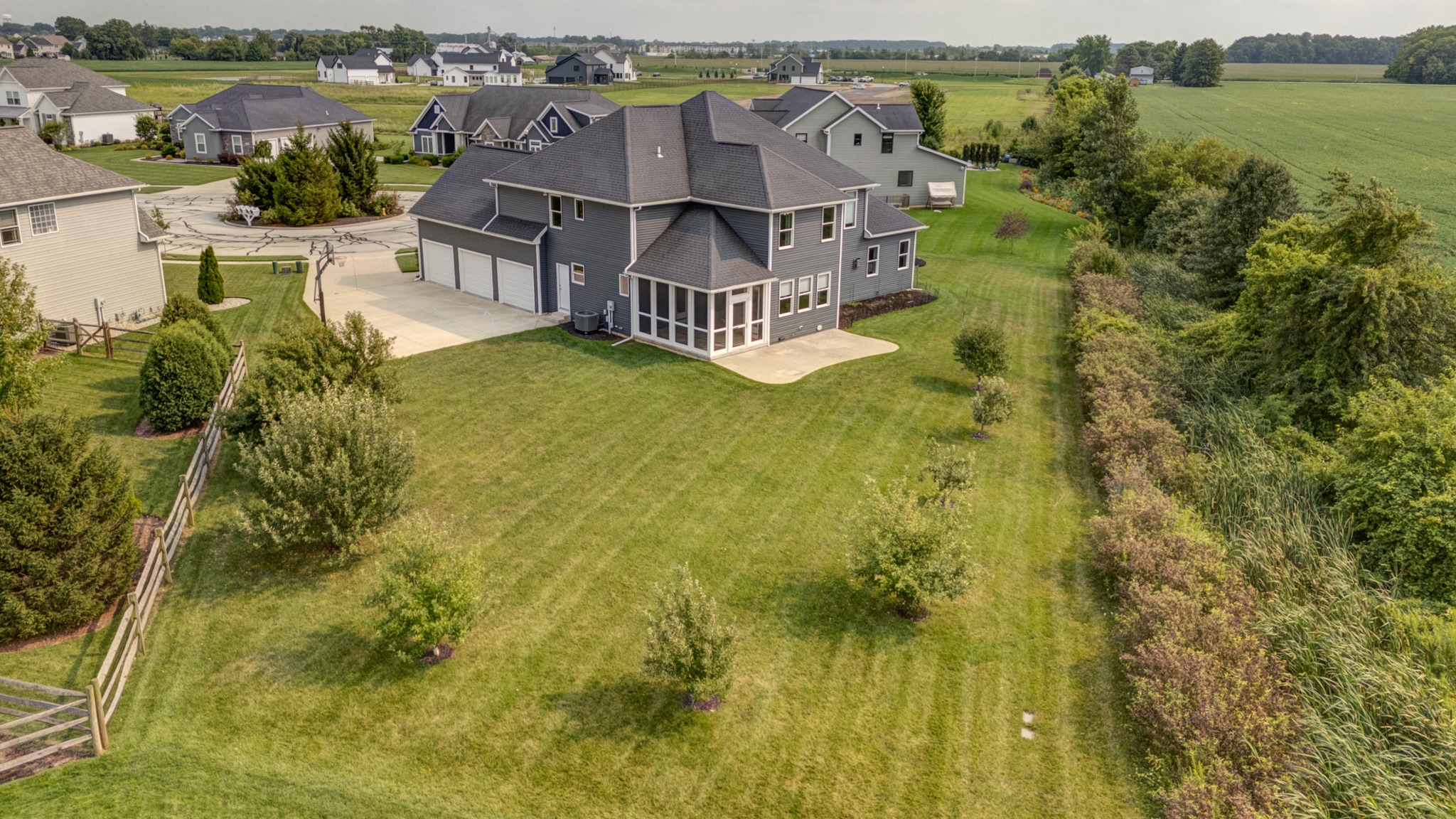 Aerial view across the spacious backyard, screened porch, patio and natural border