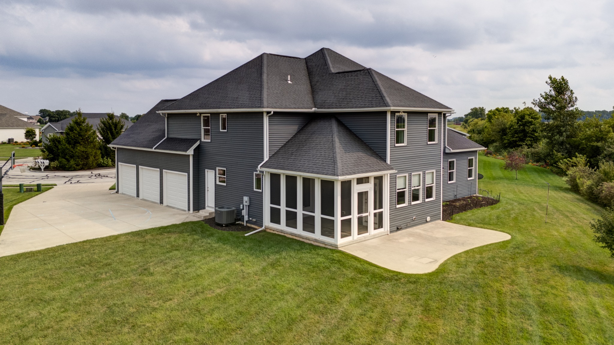 Rear exterior view showing the three-car garage, screened porch, patio and lawn