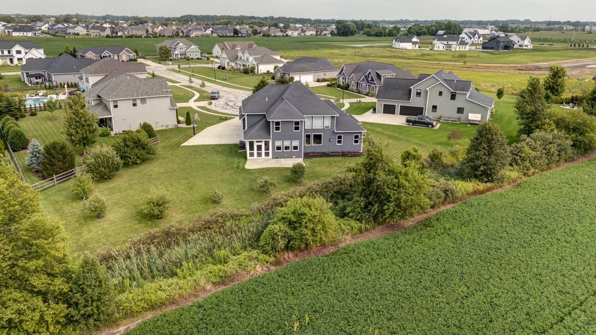 Wide aerial view of 8740 Treviso Circle, its natural border, open fields and surrounding neighborhood